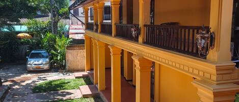 A yellow building with a covered walkway and a car parked outside.