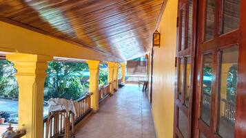 A covered corridor with wooden ceiling and yellow walls, leading to a door with windows.