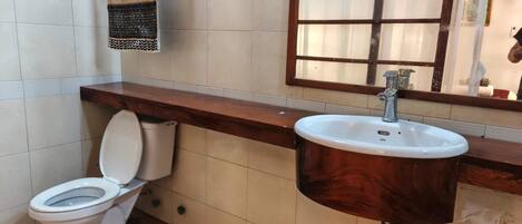 A bathroom with a toilet, a sink, and a window.