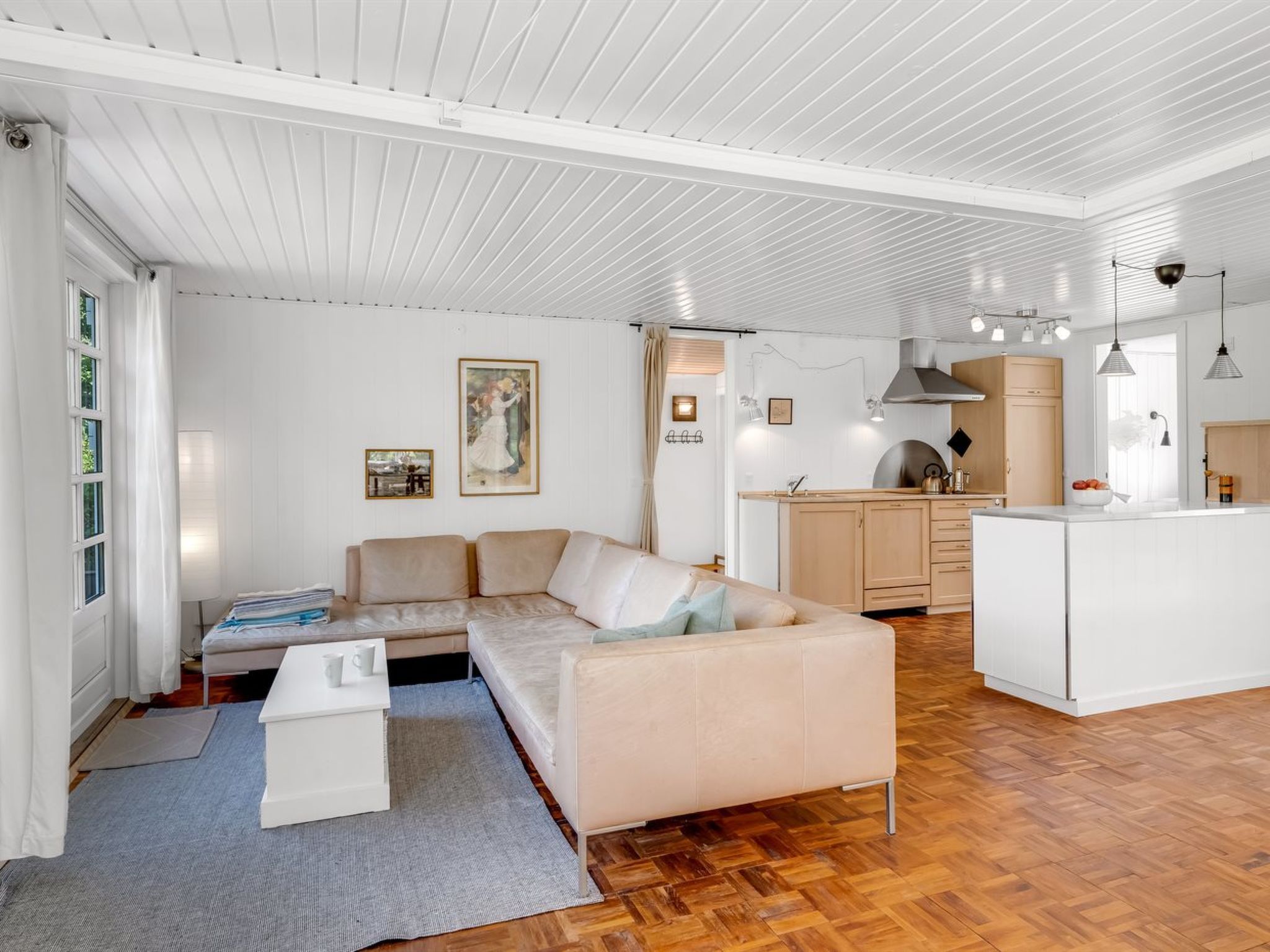 Uma sala de estar moderna com sofá, mesa de centro e área de cozinha com fogão e armários.