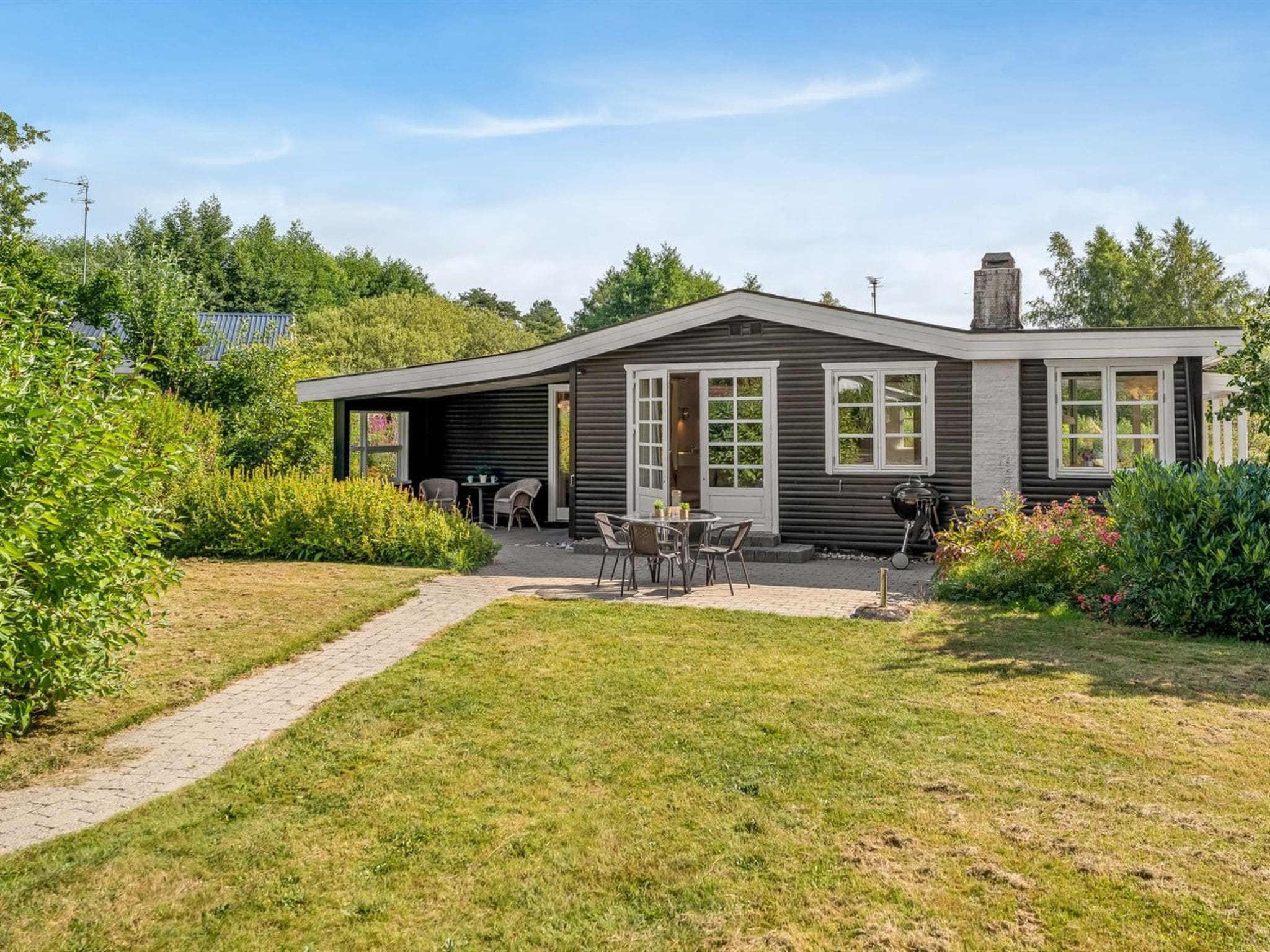 Une maison moderne à deux étages, dotée d’un patio, d’une cheminée et d’un jardin.