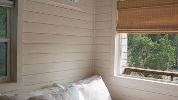 A bedroom with a bed, two windows, and a view of trees.