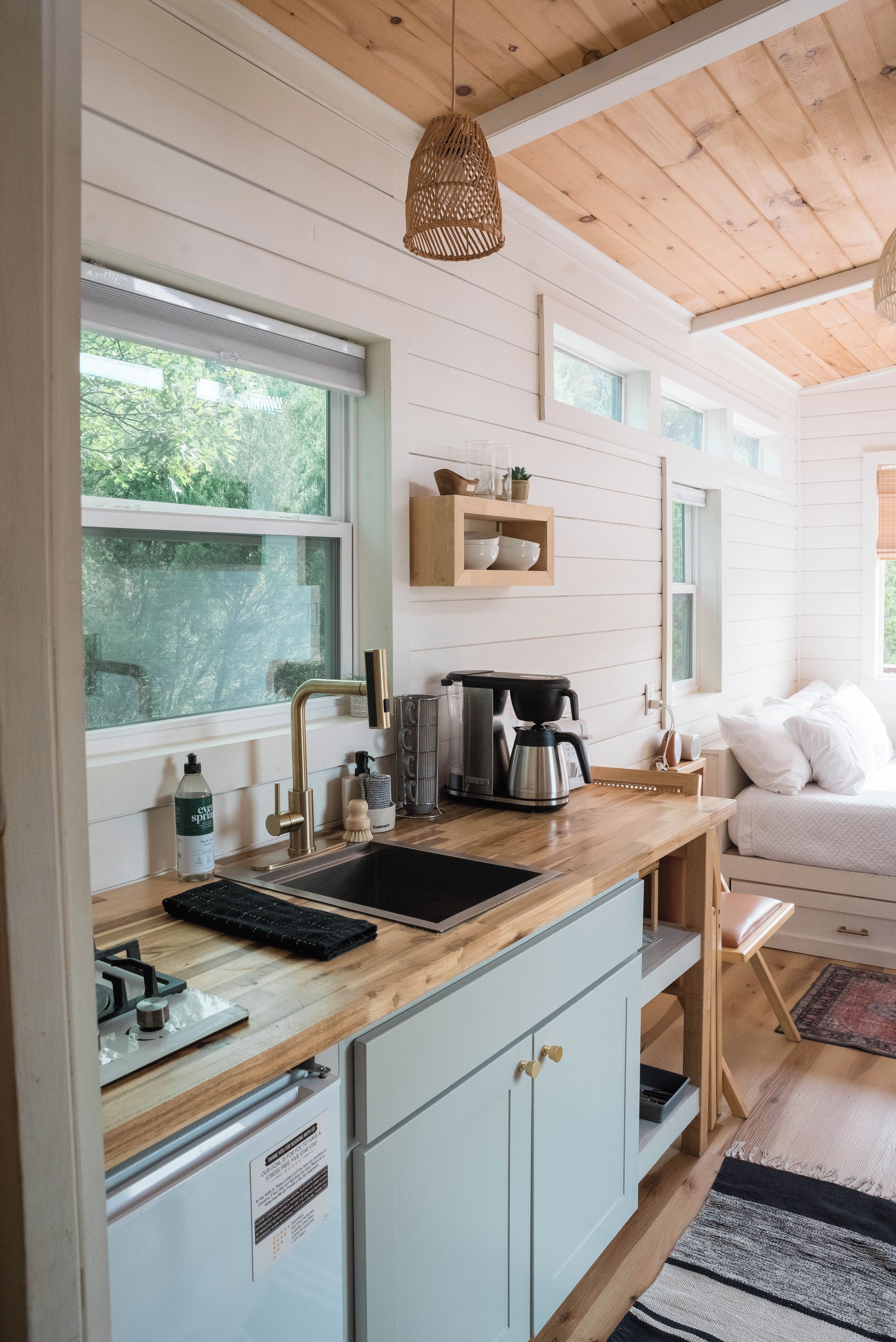A modern kitchen with a wooden countertop, a coffee maker, and a sink.