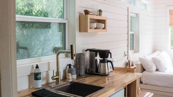A modern kitchen with a wooden countertop, a coffee maker, and a sink.