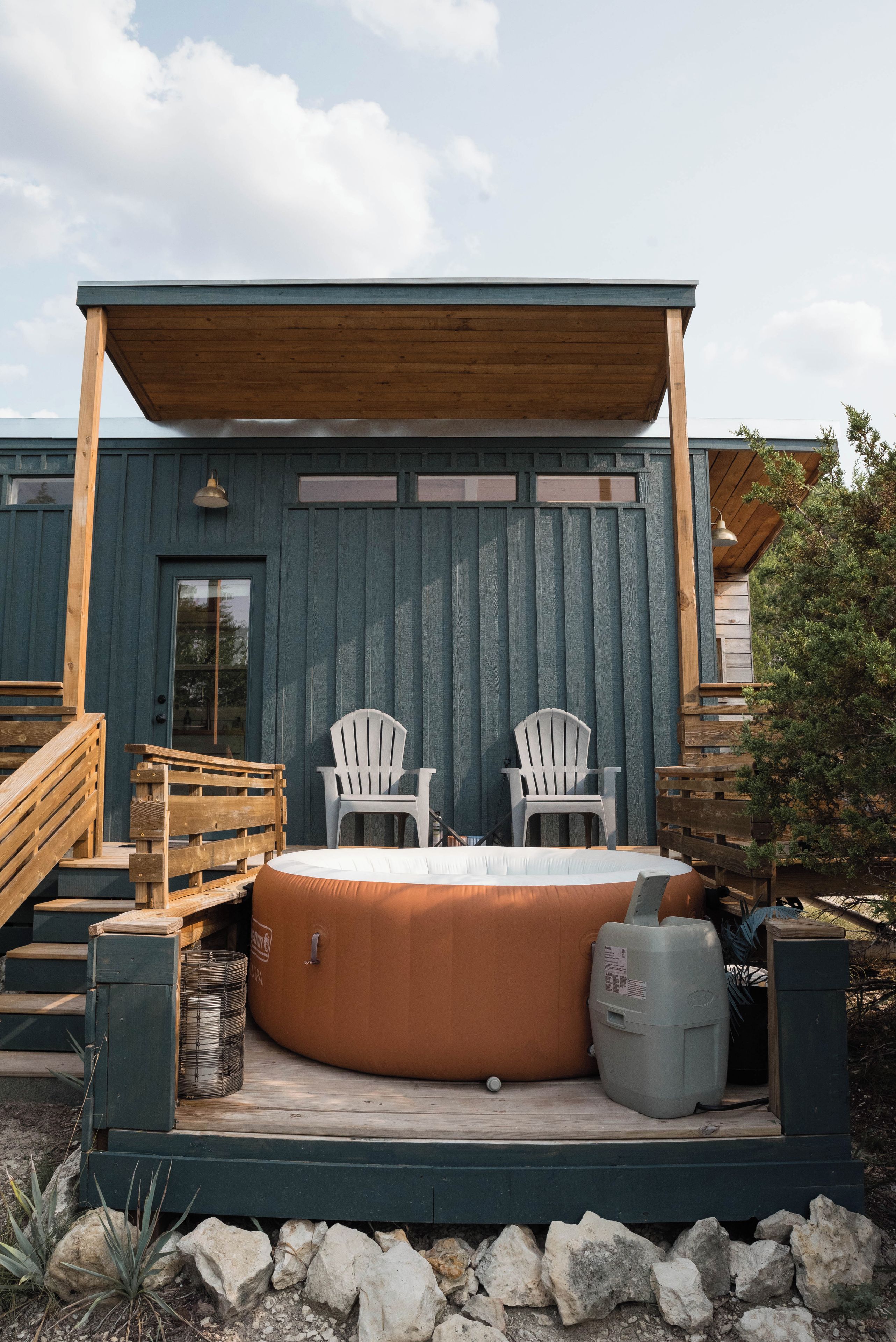 Un jacuzzi con dos sillas Adirondack, una terraza de madera y un área de patio cubierta.