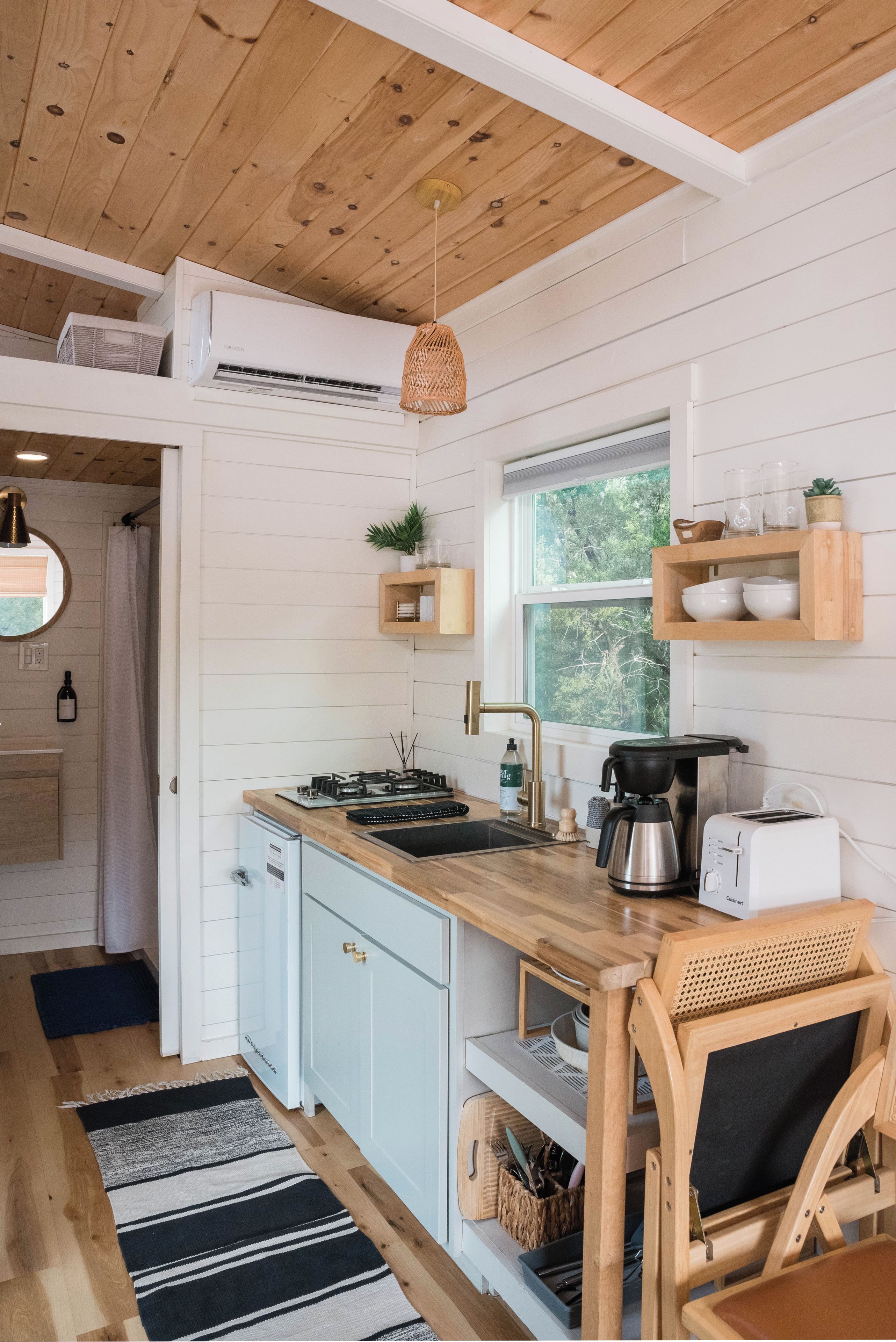 Una cocina moderna con armarios blancos, encimera de madera, estufa integrada y ventana con vistas a zonas verdes.