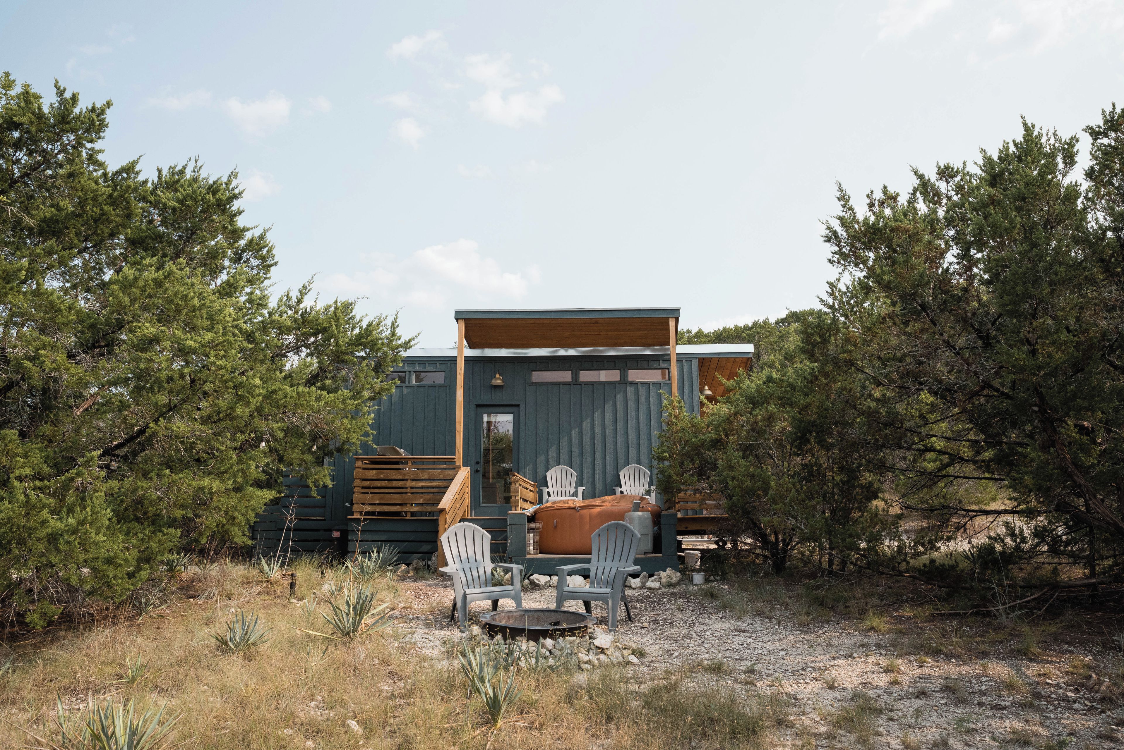 A cabin with a deck, outdoor seating, and a fire pit.