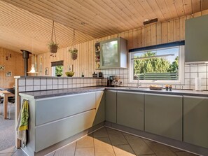 A modern kitchen with wooden paneling, a large window, and a built-in oven. - "Fabian" - 300m from the sea by Interhome (Børkop)