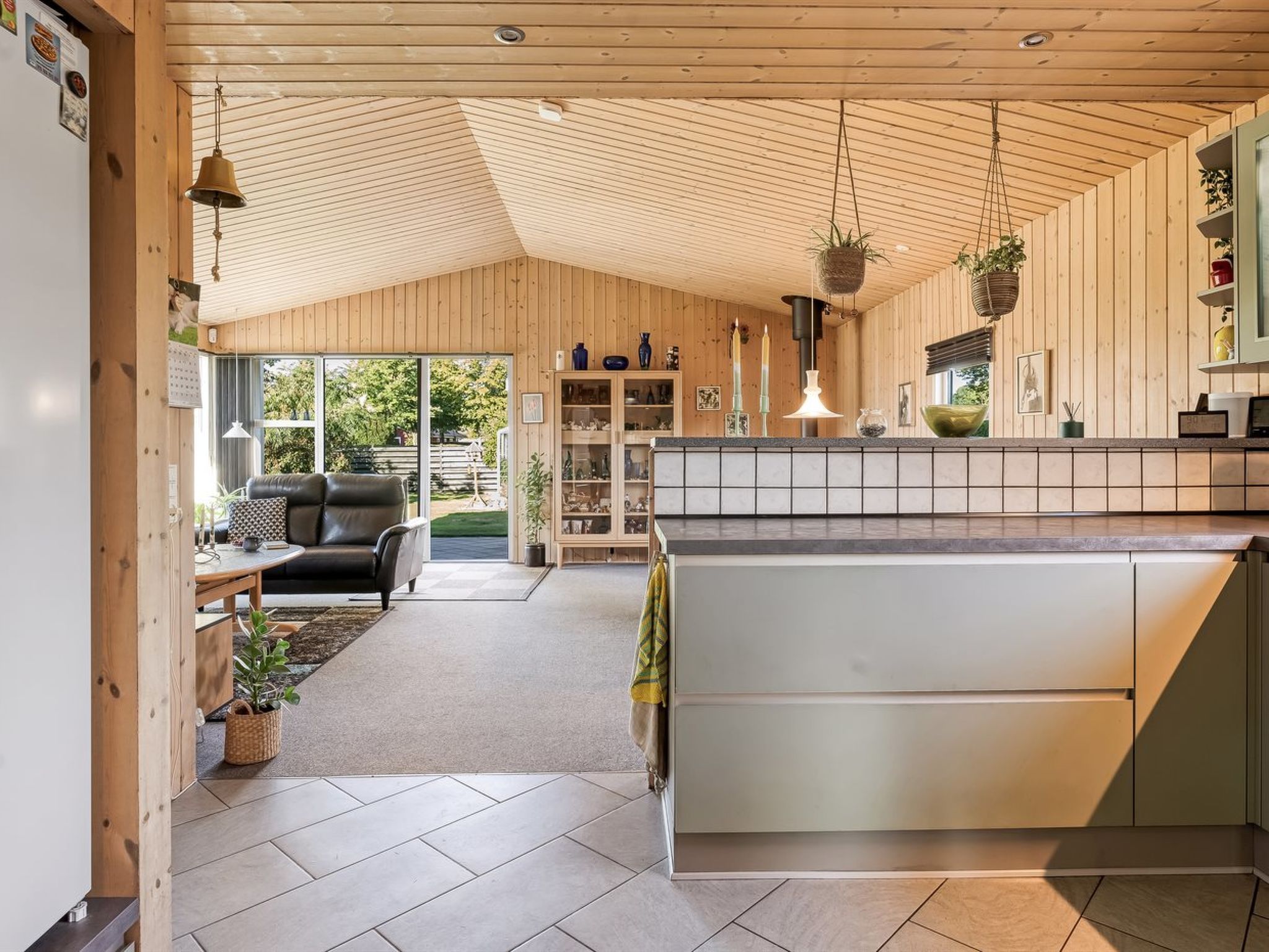 Une cuisine moderne avec des poutres en bois au plafond, un îlot central et des luminaires suspendus.