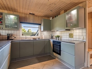 A modern kitchen with a large window, wooden ceiling, and light-colored cabinetry. - "Fabian" - 300m from the sea by Interhome (Børkop)