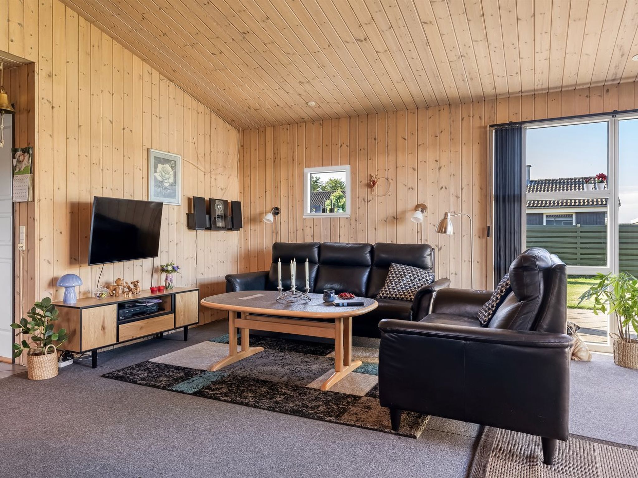Un salon chaleureux avec un décor intérieur en bois, un téléviseur à écran plat, un canapé en cuir et une table à manger.