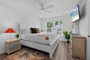 Ein Schlafzimmer mit einem Bett, Nachttisch, Lampe, Fernseher und Deckenventilator.