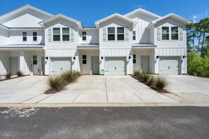 A row of white two-story houses with attached garages, a clear sky, and a well-maintained driveway. - Luxury Lost Bay Retreat in Orange Beach, AL, 3BR/2.5BA Townhome near Beach (Orange Beach)