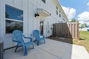 Ein zweistöckiges Gebäude mit überdachter Veranda, zwei blauen Adirondack-Stühlen und einem Holzzaun.