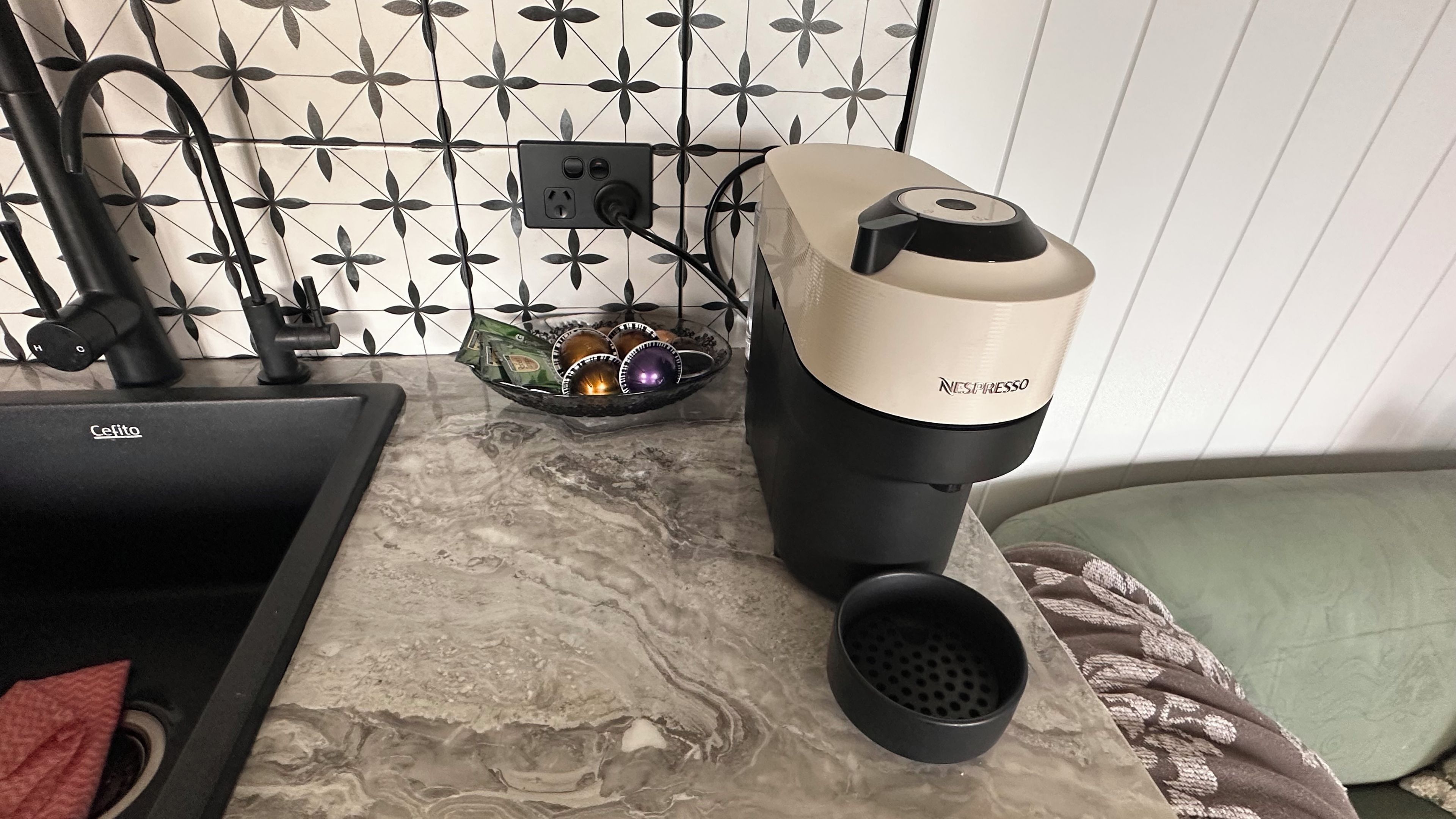 A kitchen with a sink, a coffee maker, and a decorative bowl on the counter.