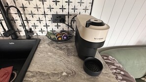 Eine Küche mit Spüle, einer Kaffeemaschine und einer dekorativen Schale auf der Arbeitsplatte.