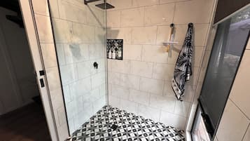 A bathroom with a tiled floor, a shower area, and a towel rack.