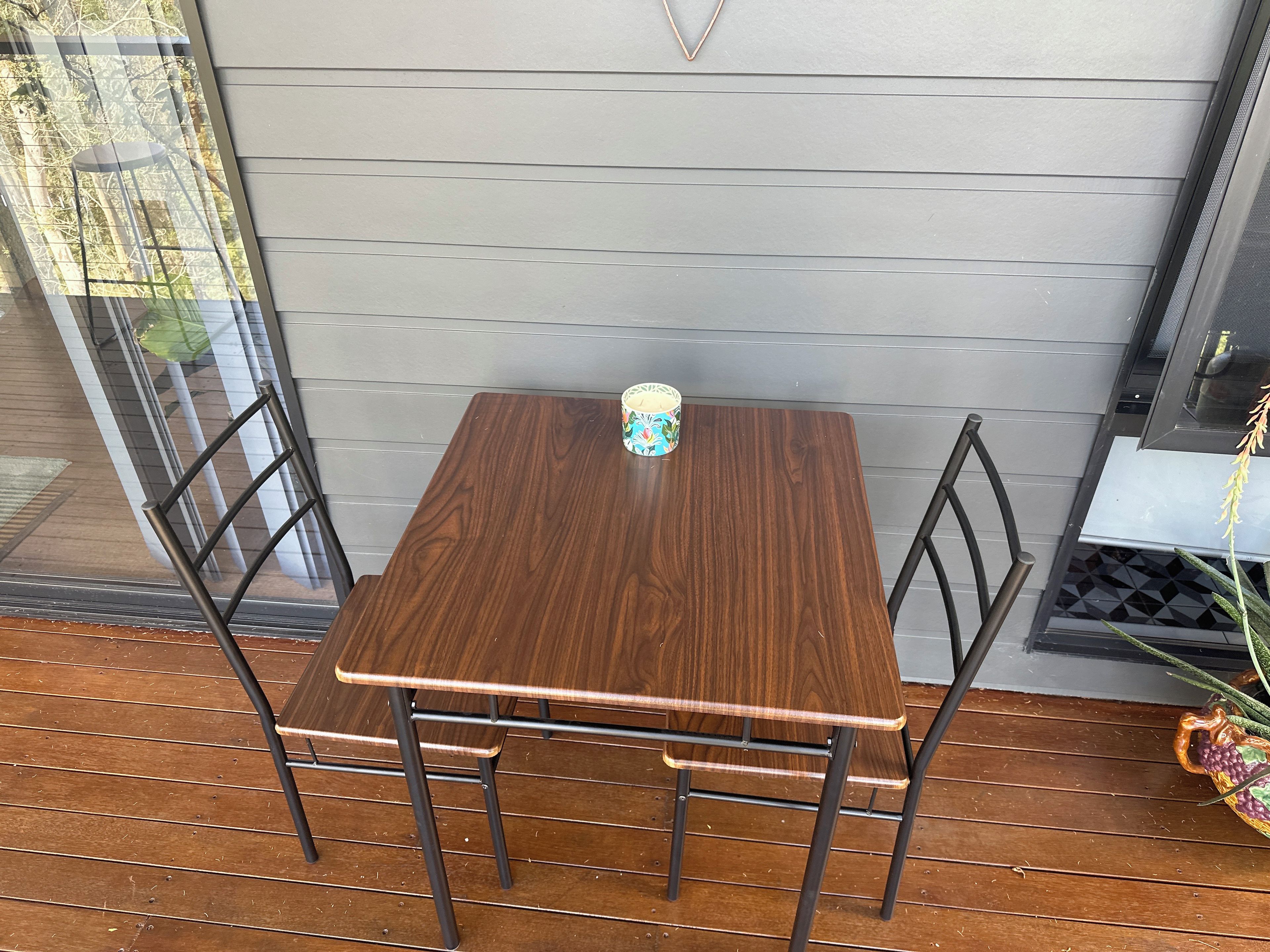 A wooden table with a metal frame and a single chair on a wooden deck.