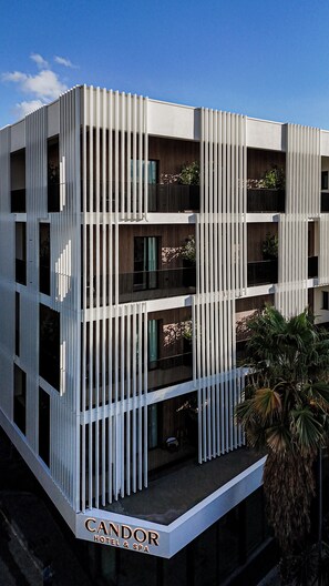 A modern hotel building with a vertical facade, balconies, and a sign indicating it is a hotel and spa. - Candor Hotel & Spa (Tirana)