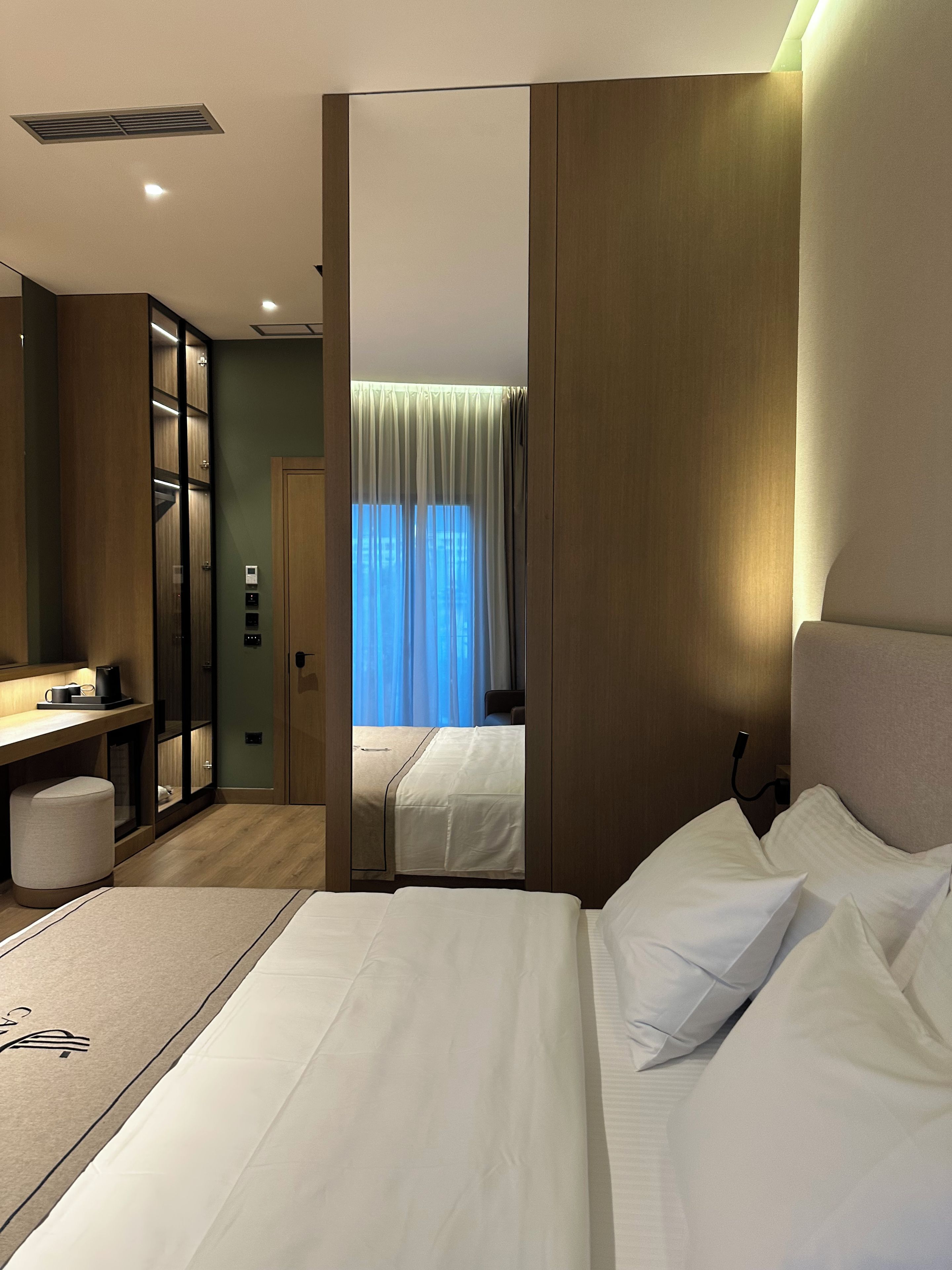 Una habitación de hotel con cama, mesita de noche y escritorio.