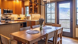 Una cocina moderna con armarios de madera, electrodomésticos de acero inoxidable y un comedor con una mesa grande y sillas.