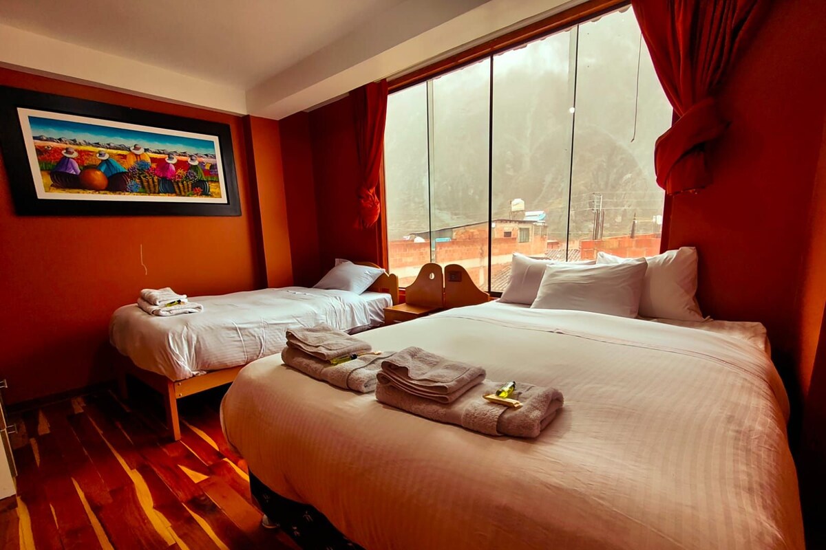 A hotel room with two beds, a large window, and a painting on the wall.