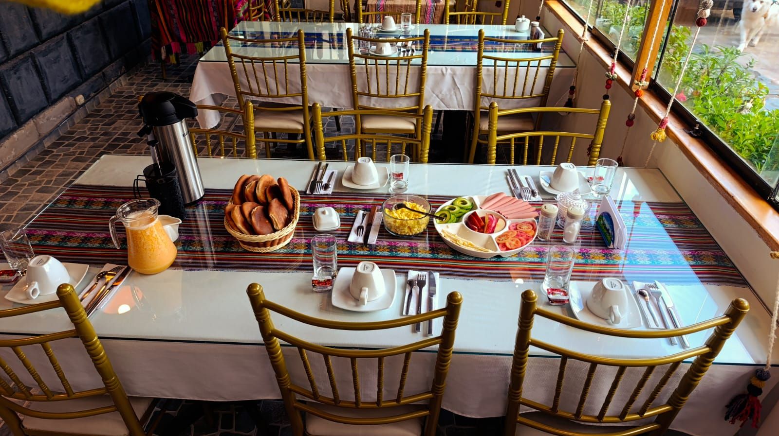 A dining table set with plates, cutlery, and a pitcher of orange juice.