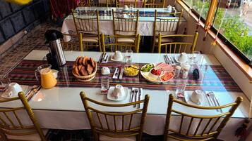 A dining table set with plates, cutlery, and a pitcher of orange juice.