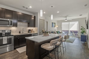 Una cocina moderna con armarios oscuros, electrodomésticos de acero inoxidable y una isla central con taburetes de bar.