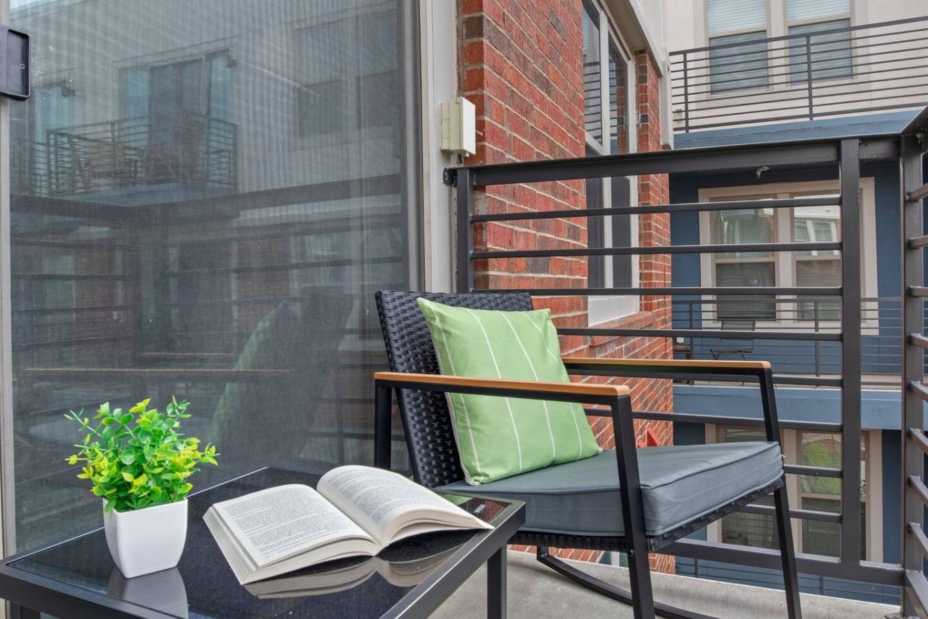 A balcony with a chair, a table, and a potted plant.
