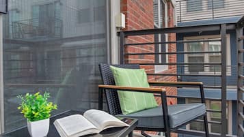 A balcony with a chair, a table, and a potted plant.