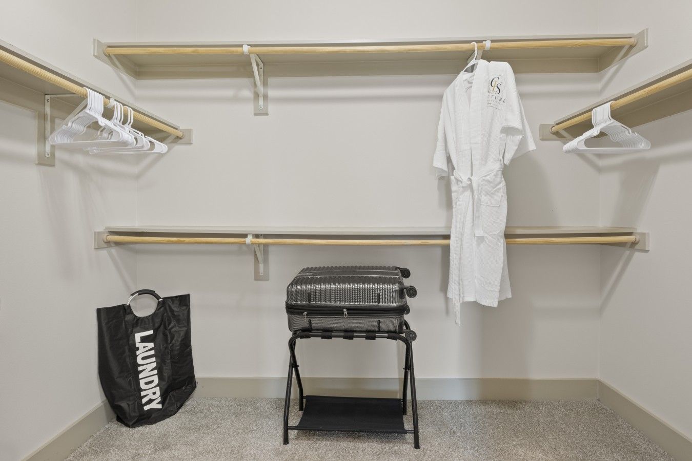 A room with a built-in closet, a luggage trolley, and a laundry bag.
