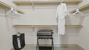 A room with a built-in closet, a luggage trolley, and a laundry bag.