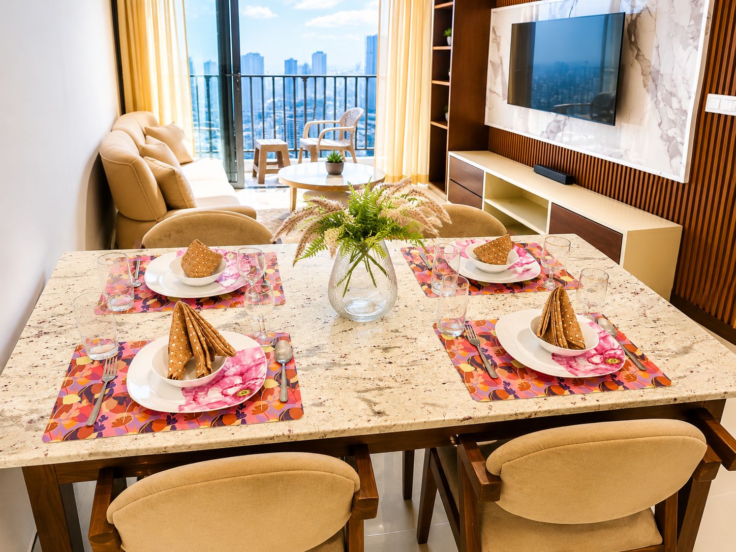 A dining area with a table set for four, a city view, a sofa, and a TV.