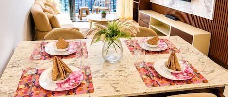 A dining area with a table set for four, a city view, a sofa, and a TV.