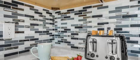 A kitchen with a modern design, featuring a toaster, a mug, and a plate with toast and strawberries.