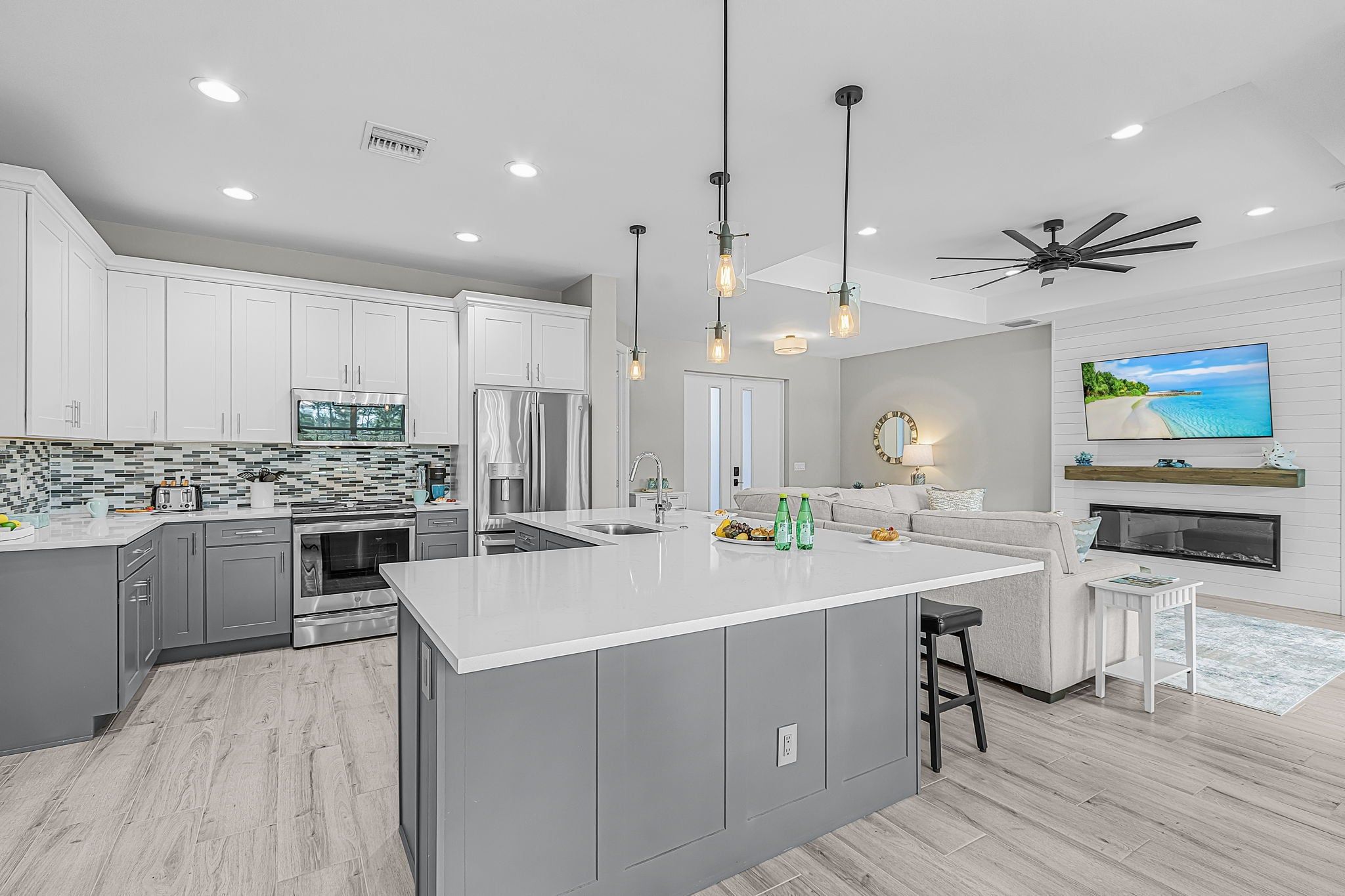A modern kitchen with a large island, stainless steel appliances, and pendant lighting.