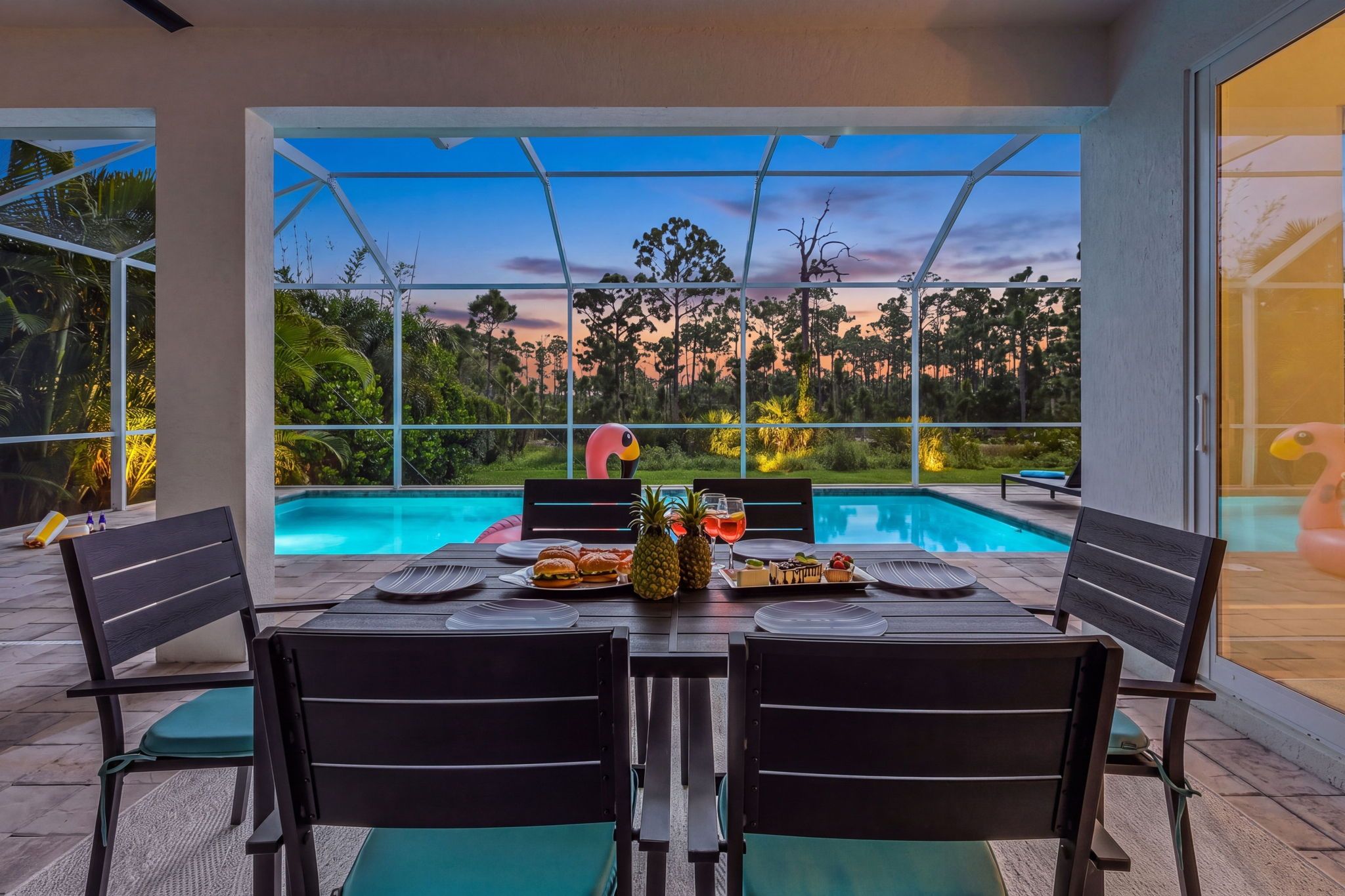 An outdoor dining area with a pool view, a table set for four, and a large flamingo decoration.