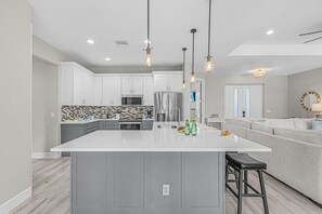 A modern kitchen with a central island, stainless steel appliances, and pendant lighting. - Sunrise Oasis Pool Escape with Views and Fun for the Whole Family - Villa Sunrise Oasis - Roelens (Cape Coral)