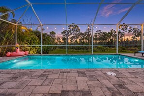 Una piscina amb una superfície d'aigua blava cristal·lina, envoltada per una zona coberta amb estructura metàl·lica i llums enfilades.