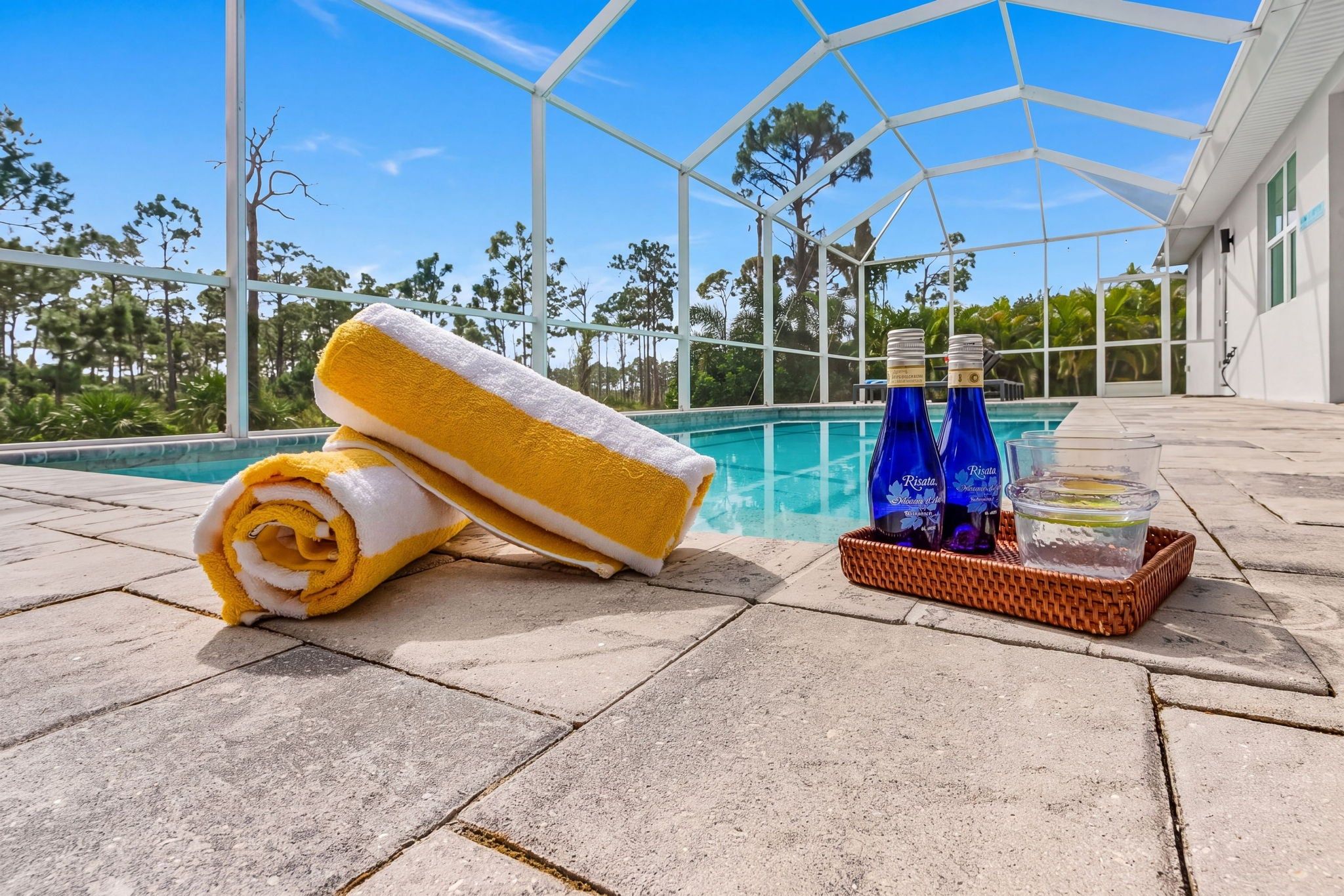 A poolside area with a towel, two bottles, and a glass of water.