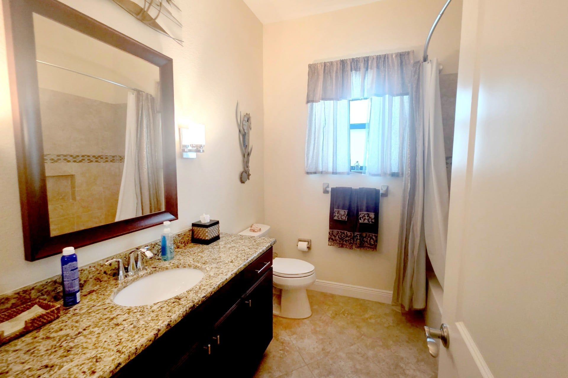 A bathroom with a sink, mirror, toilet, and shower curtain.