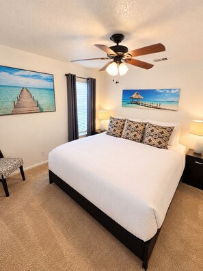 A bedroom with a bed, a ceiling fan, a nightstand, a chair, and two wall-mounted paintings. - Howdy, San Antonio! Cozy 3BR• Sleeps 8 • 5 Mins From Airport (San Antonio)