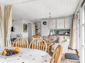 A dining area with a table set for two, a floral sofa, wooden chairs, and a kitchen in the background. - "Laurine" - 500m from the sea by Interhome (Sydals)