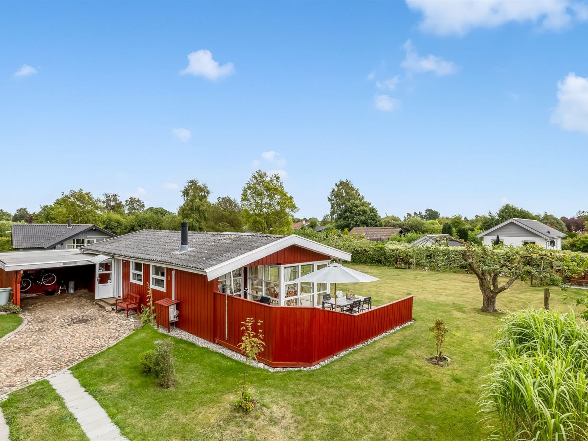 A residential property with a red exterior, a covered patio, and a well-maintained lawn.