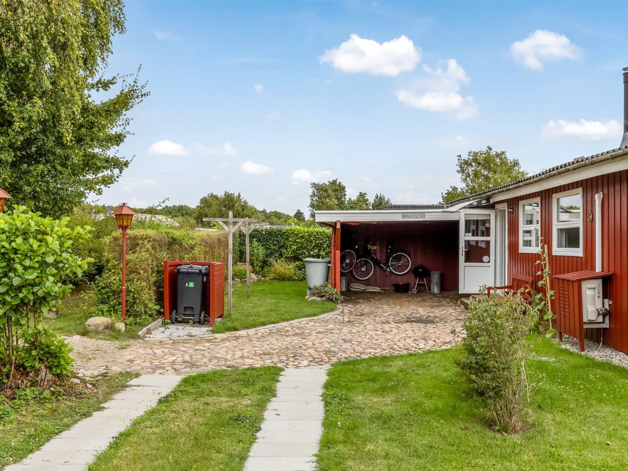 A residential property with a garage, a pathway leading to the entrance, and a small garden area.