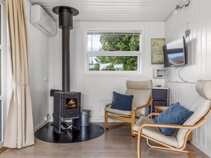 A cozy room with a wood-burning stove, two chairs, a TV, and a window with a view of greenery. - "Laurine" - 500m from the sea by Interhome (Sydals)