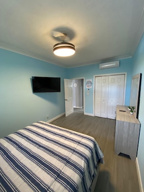 A bedroom with a bed, a TV, a ceiling fan, and a wardrobe. - Charming apartment with AC in vibrant Nassau perfect for couples, relaxing. (Nassau)