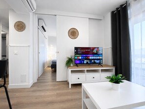 A modern living room with a flat-screen TV, a white entertainment unit, and a dining area. - Ocean House Apartment Sea View Block 2, 5th Floor (Torremolinos)