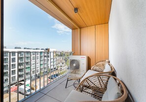 A balcony with wicker furniture, a white inverter air conditioner, and a view of a cityscape. - Mokotów Residence Apartment (Warszawa)